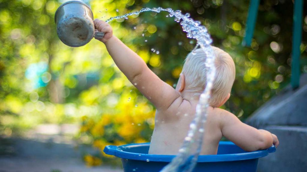 baby playing in water bucket